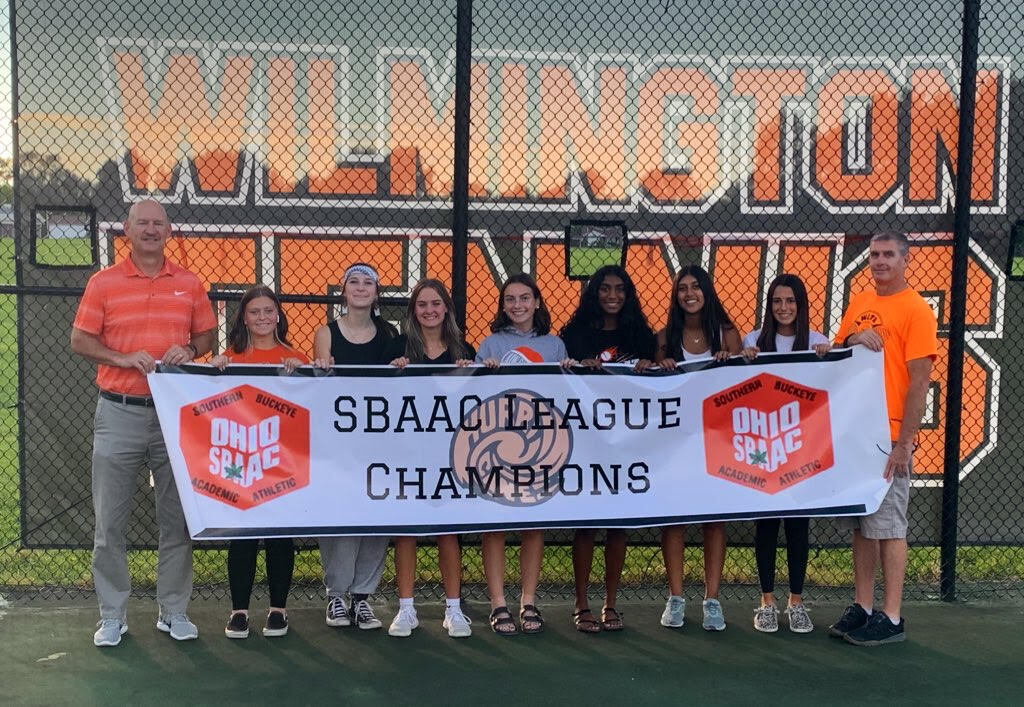 7 high school girls, tennis players with 2 male coaches holding Champions sign